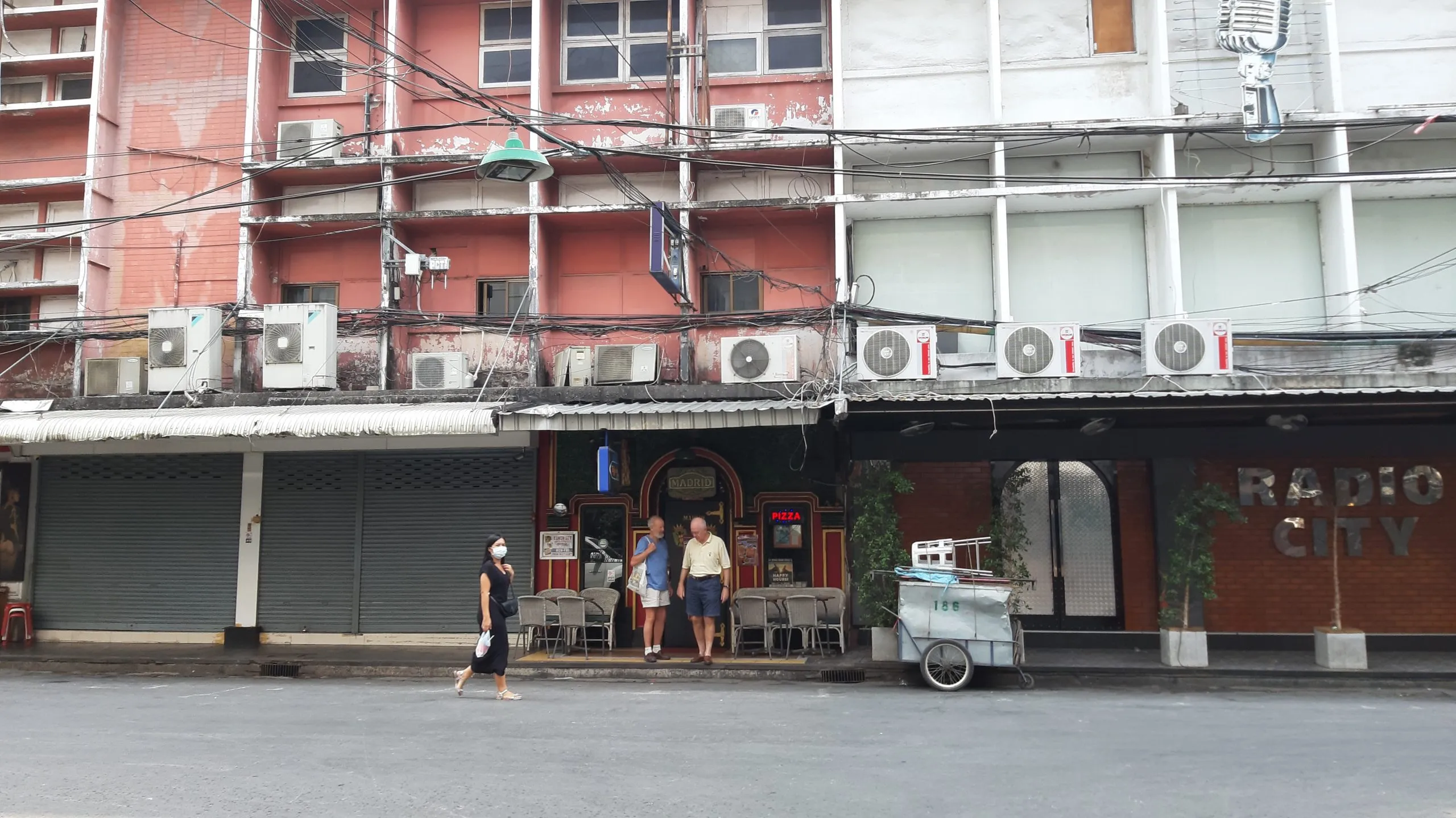 Patpong in daylight: shuttered bars and shophouses along an empty side street.